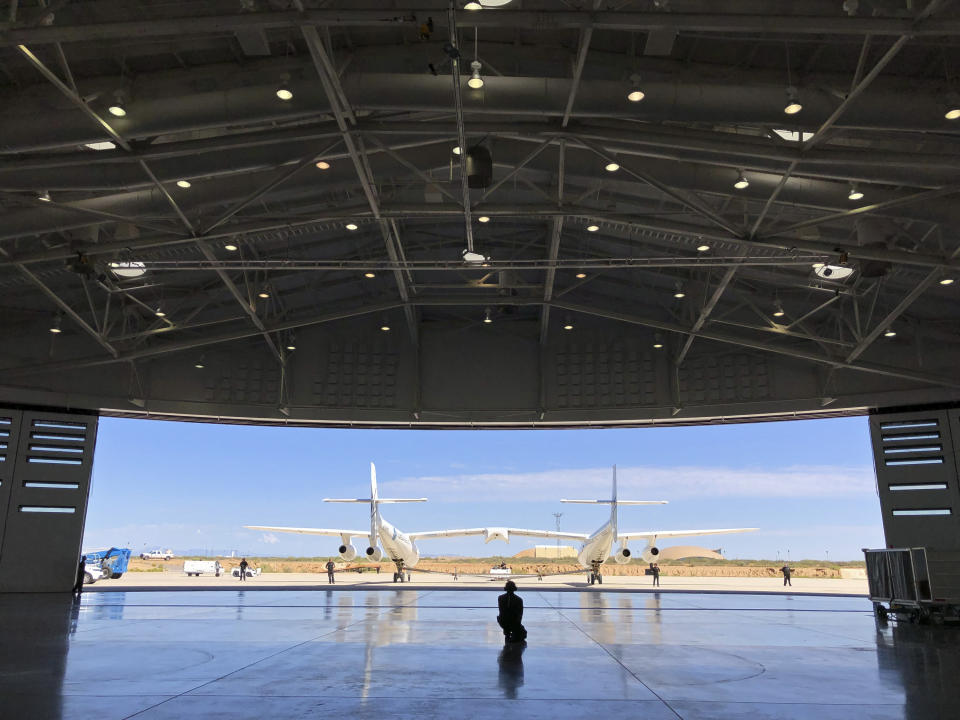 Virgin Galactic ground crew guide the company's carrier plane into the hangar at Spaceport America following a test flight over the desert near Upham, New Mexico, on Thursday, Aug. 15, 2019. The carrier plane is now permanently based at the spaceport after arriving earlier this week. (AP Photo/Susan Montoya Bryan)