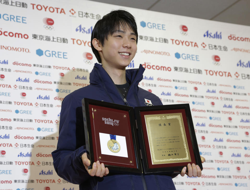 Yuzuru Hanyu of Japan holds up a replica of his gold medal after a news conference at the Japan House at the 2014 Winter Olympics, Saturday, Feb. 15, 2014, in Sochi, Russia. Hanyu won the gold medal in the men's free skate figure skating final. (AP Photo/Morry Gash)