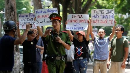 A policeman tries to stop anti-China protesters holding placards during a demonstration in front of the Philippines embassy in Hanoi, Vietnam July 17, 2016. REUTERS/Kham