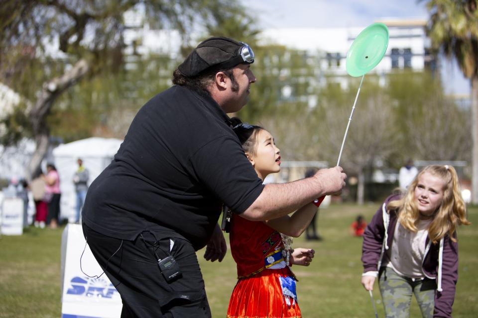 Julius Szakolczai teaches Enze Yu, 9, how to use one of the toys for sale at his tent during the Chinese Week Culture and Cuisine Festival on Feb.10, 2019, in Margaret T. Hance Park.