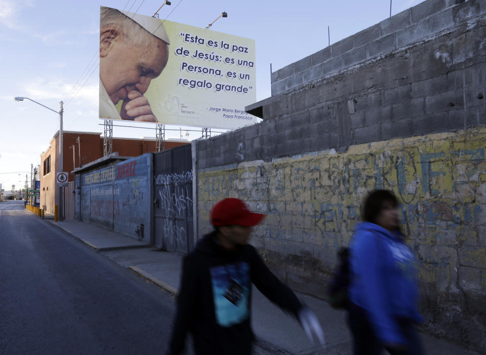 FILE - In this Feb. 17, 2016, file photo, people pass an image of Pope Francis on their way to a route where he is scheduled to pass in Cuidad Juarez, Mexico. The sign displays a quote in Spanish by Pope Francis that reads: "This is the peace of Jesus: he's a person, it's a big gift." (AP Photo/Gregory Bull, File)