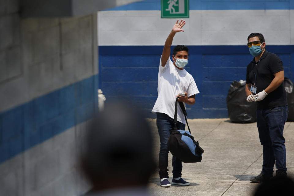 A deported man waves to his family who brought him food, at the site where Guatemalans returned from the U.S. are being held in Guatemala City, Friday, April 17, 2020. Recently deported Guatemalans were placed in a athletic dorm facility to wait for the results of their tests for the new coronavirus. (AP Photo/Moises Castillo)