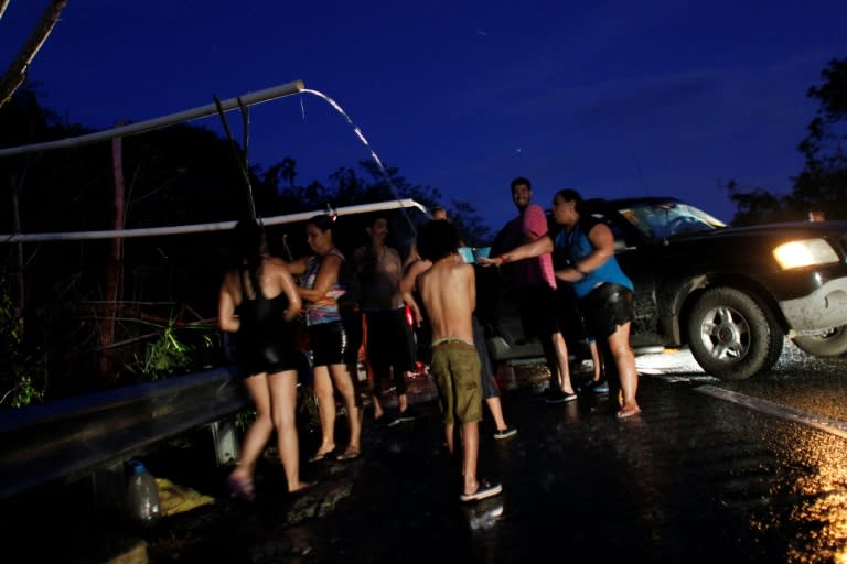 A month after Hurricane Maria struck Puerto Rico, people collect water while others bathe using an improvised pipe system drawing on a mountain creek