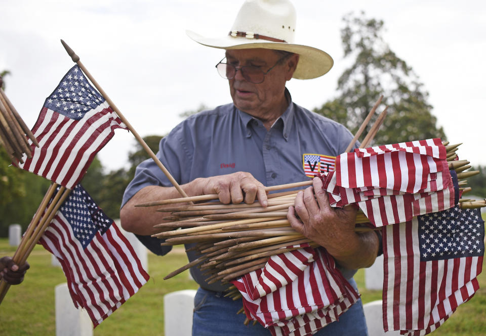 <p>Doug McCallister passes out U.S. flags Saturday, May 26, 2018 for volunteers to place in front of the tombstones at the Natchez National Cemetery in Natchez, Miss., as the community honors those who died in service to their country. (Photo: Nicole Hester/The Natchez Democrat via AP) </p>