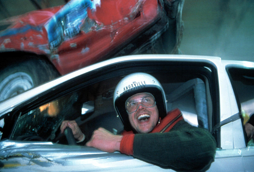 Johnny Knoxville in a car, wearing a helmet