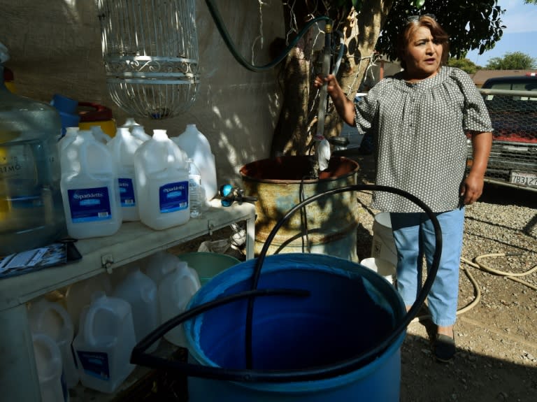 Maria Jimenez demonstrates how they pump bottled water up to a storage tank on the roof of their rented house to wash in the drought affected town of Monson, California on June 23, 2015