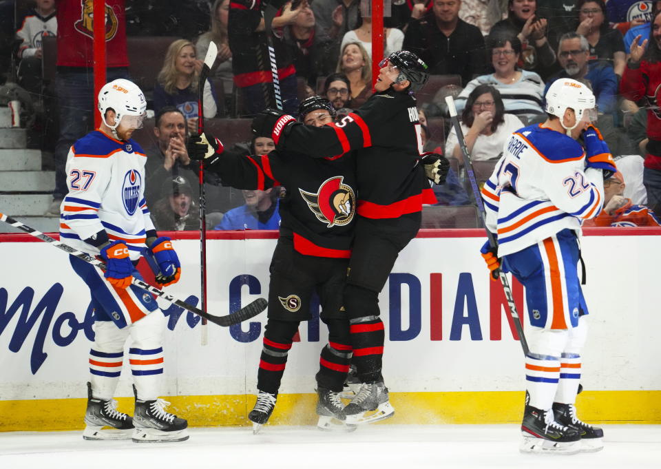 Ottawa Senators defenseman Erik Brannstrom (26) and teammate Nick Holden (5) celebrate a goal as Edmonton Oilers defenseman Brett Kulak (27) and Tyson Barrie (22) skate past during the second period of an NHL hockey game in Ottawa on Saturday, Feb. 11, 2023. (Sean Kilpatrick/The Canadian Press via AP)