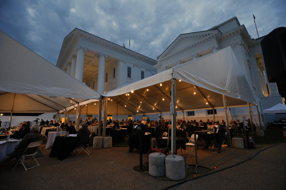 House of Delegates members meet into the evening as they neared the end of the veto session at the Virginia State Capitol in Richmond, Va., Wednesday, April 22, 2020. The House members were meeting outside under a tent instead of the House Chamber in order to practice social distancing due to the COVID-19 outbreak. (Bob Brown/Richmond Times-Dispatch via AP)
