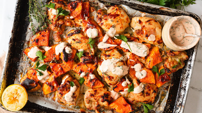 Baked chicken and squash with yogurt on baking sheet