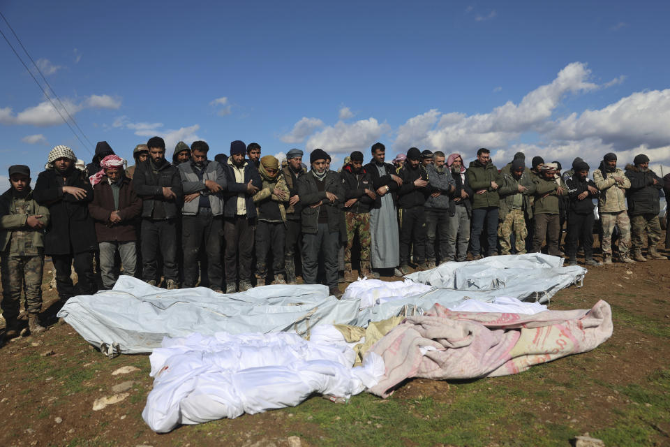 Mourners pray over coffins of family members who died in a devastating earthquake that rocked Syria and Turkey at a cemetery in the town of Jinderis, Aleppo province, Syria, Tuesday, Feb. 7, 2023. The quake has brought down thousands of buildings and killed thousands of people. In Syria, it also came on the heels of over a decade of conflict and a crippling economic crisis. (AP Photo/Ghaith Alsayed)