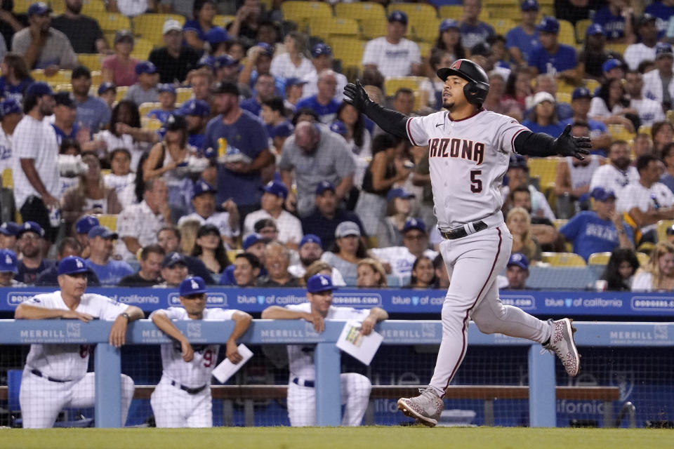 Arizona Diamondbacks' Eduardo Escobar gestures before scoring on a two-run home run while members of the Los Angeles Dodgers watch from the dugout during the fifth inning of a baseball game Friday, July 9, 2021, in Los Angeles. (AP Photo/Mark J. Terrill)