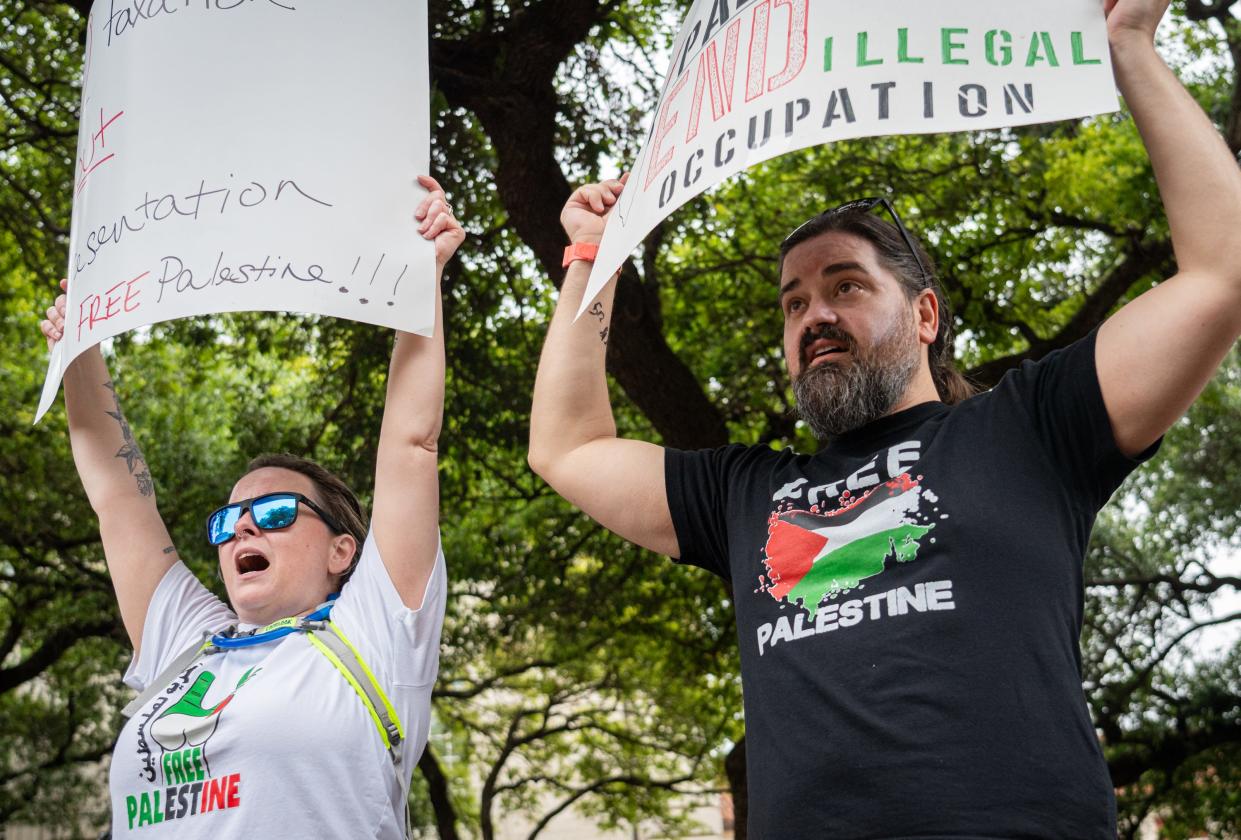 Jennifer Harper, left, and Kevin P. hold signs at a pro-Palestine protest on the University of Texas lawn, Sunday, May 5, 2024 in Austin, Texas.