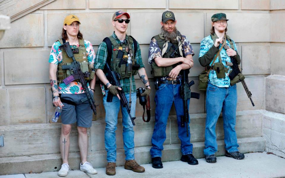  In this file photo taken on May 20, 2020 Armed protesters demonstrate during the Michigan Conservative Coalition organized "Operation Haircut" outside the Michigan State Capitol in Lansing, Michigan. Under their bulletproof vests and assault rifles, all four wear brightly-coloured Hawaiian shirts - Jeff Kowalsky/AFP