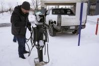 Lawrence Ziehr, project manager for energy recovery on GM's electric vehicles, connects a Hummer EV to a charging station, Wednesday, Feb. 22, 2023, in Sault Ste. Marie, Mich. Some automakers and drivers fear lower battery range in the cold could limit acceptance of electric cars, trucks and buses, at a time when emissions from transportation must go down sharply to address climate change. (AP Photo/Carlos Osorio)