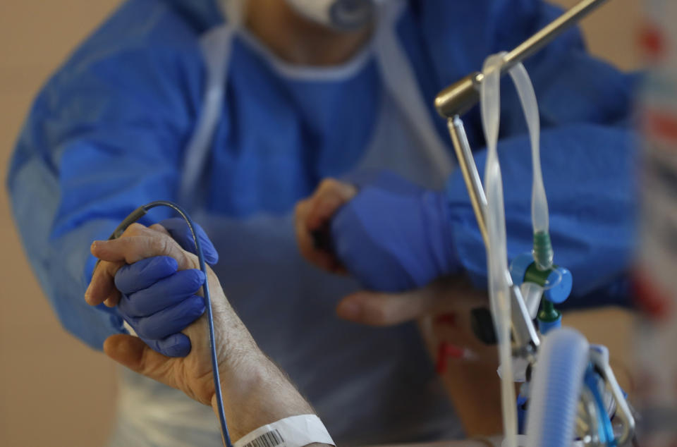 A healthcare worker attends to a COVID-19 patient in an intensive care unit (ICU) at the General University Hospital in Prague, Czech Republic, Tuesday, April 7, 2020. The new coronavirus causes mild or moderate symptoms for most people, but for some, especially older adults and people with existing health problems, it can cause more severe illness or death. (AP Photo/Petr David Josek)