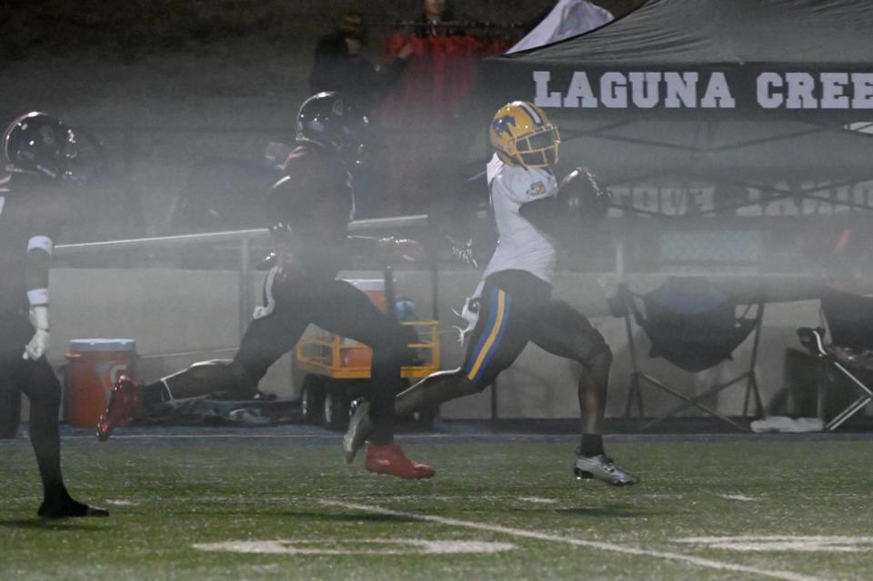 The Grant Pacers running back Wayshawn Parker (1) carries the ball for 82 yards before being pushed out of bounds at the 4-yard line by the Laguna Creek Cardinals’ Halim Tholley (4) in the first half on Friday at Cosumnes River College.