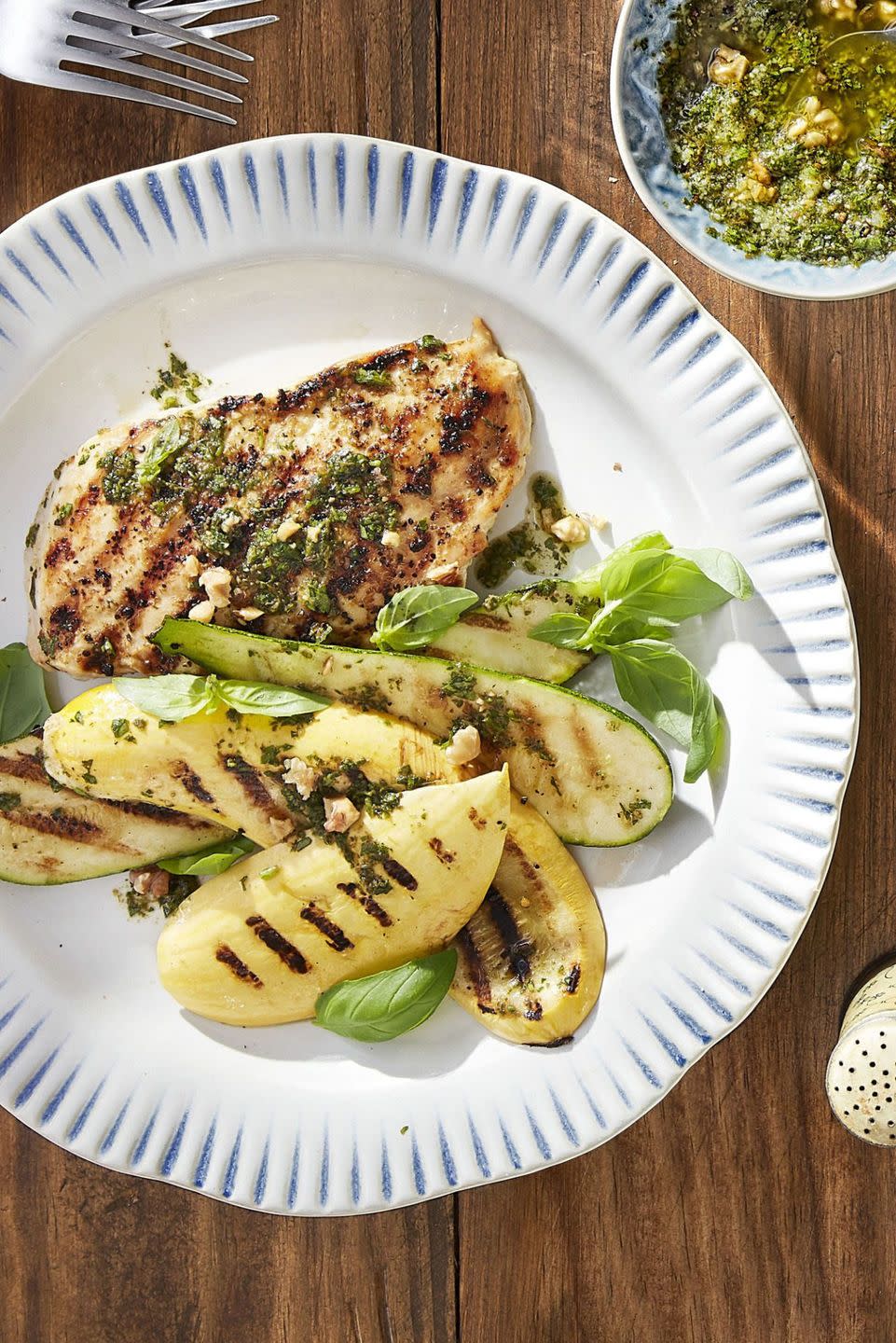 grilled pesto chicken with summer squash on a white plate