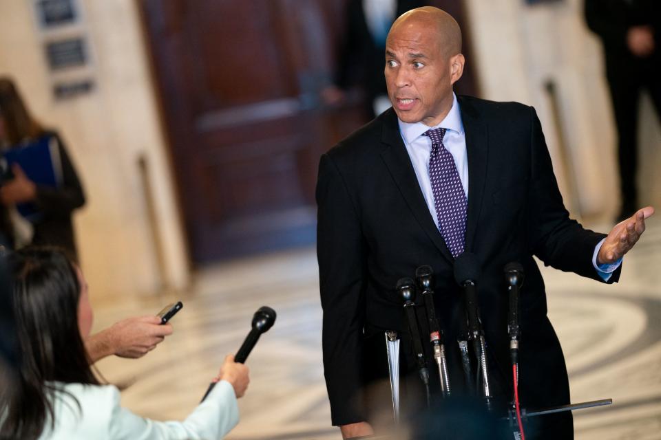 Senator Cory Booker stands at a podium while speaking to the press inside the Capitol.