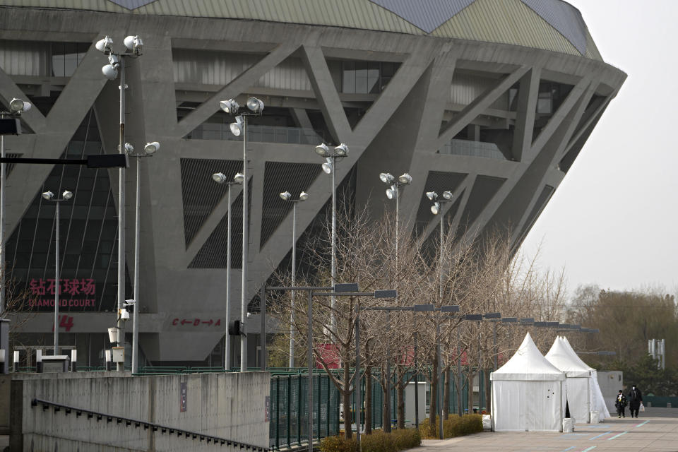 People walk by the Diamond Court at the National Tennis Center in Beijing, Sunday, Nov. 21, 2021. According to photos released by the organizer, missing tennis star Peng Shuai reappeared in public Sunday at a youth tournament in the court compound in Beijing, as the ruling Communist Party tried to quell fears abroad while suppressing information in China about Peng after she accused a senior leader of sexual assault. (AP Photo/Andy Wong)