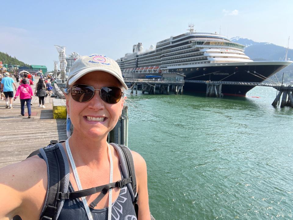 rebecca posing in front of a cruise ship wearing a tank top