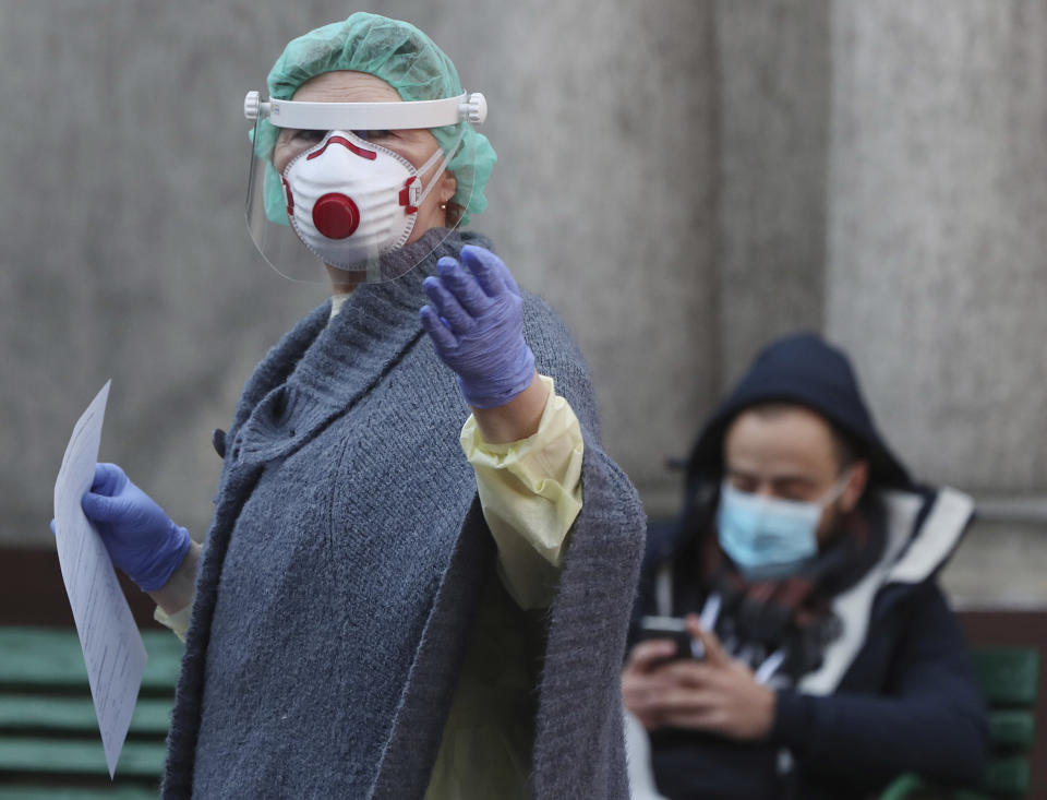 A nurse in protective headgear with documents and patient waiting for his coronavirus test at the contagious diseases hospital in Warsaw, Poland, Monday, March 16, 2020.For some, especially older adults and people with existing health problems, it can cause more severe illness, including pneumonia.(AP Photo/Czarek Sokolowski)