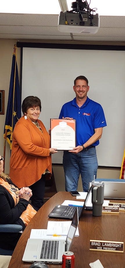 Dr. Jennifer Horvath, regional director for Cognia (formerly NCA Accreditation), presents a plaque to Centerville-Abington Community Schools Board President Todd Duke at the school board meeting, Wednesday, Oct. 18, 2023.