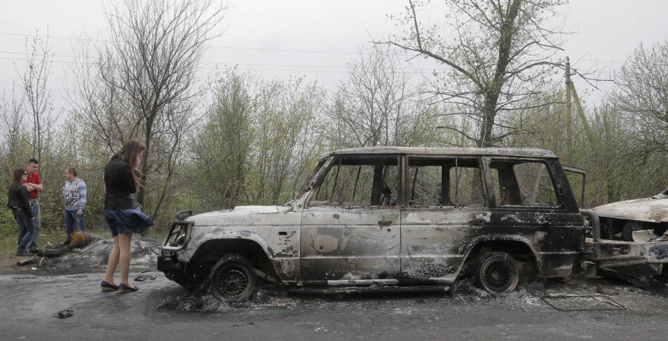 Local residents inspect burnt out cars after a night fight at the check point which was under the control of pro-Russian activists in the village of Bulbasika near Slovyansk, Ukraine, Sunday, April 20, 2014. At least one person was killed in the clash. Pro-Russian insurgents defiantly refused to surrender their weapons or give up government buildings in eastern Ukraine, despite a diplomatic accord reached in Geneva and overtures from the government in Kiev. (AP Photo/Efrem Lukatsky)