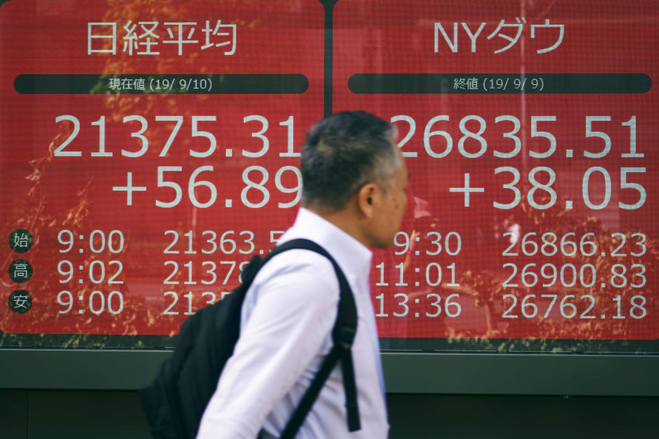 A man walks past an electronic stock board showing Japan's Nikkei 225 index and New York Dow Jones index at a securities firm in Tokyo Tuesday, Sept. 10, 2019. Asian shares were mixed Tuesday after a day of listless trading on Wall Street, as investors awaited signs on global interest rates.(AP Photo/Eugene Hoshiko)