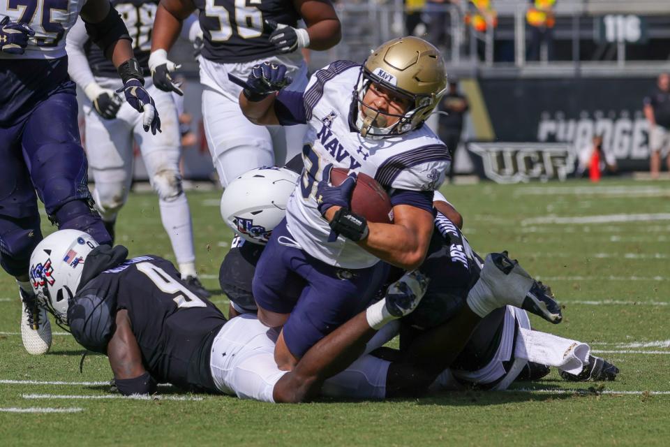 Nov 19, 2022; Orlando, Florida, USA; Navy Midshipmen fullback Anton Hall Jr. (34) is tackled by UCF Knights defensive back Justin Hodges (12) during the second quarter at FBC Mortgage Stadium. Mandatory Credit: Mike Watters-USA TODAY Sports