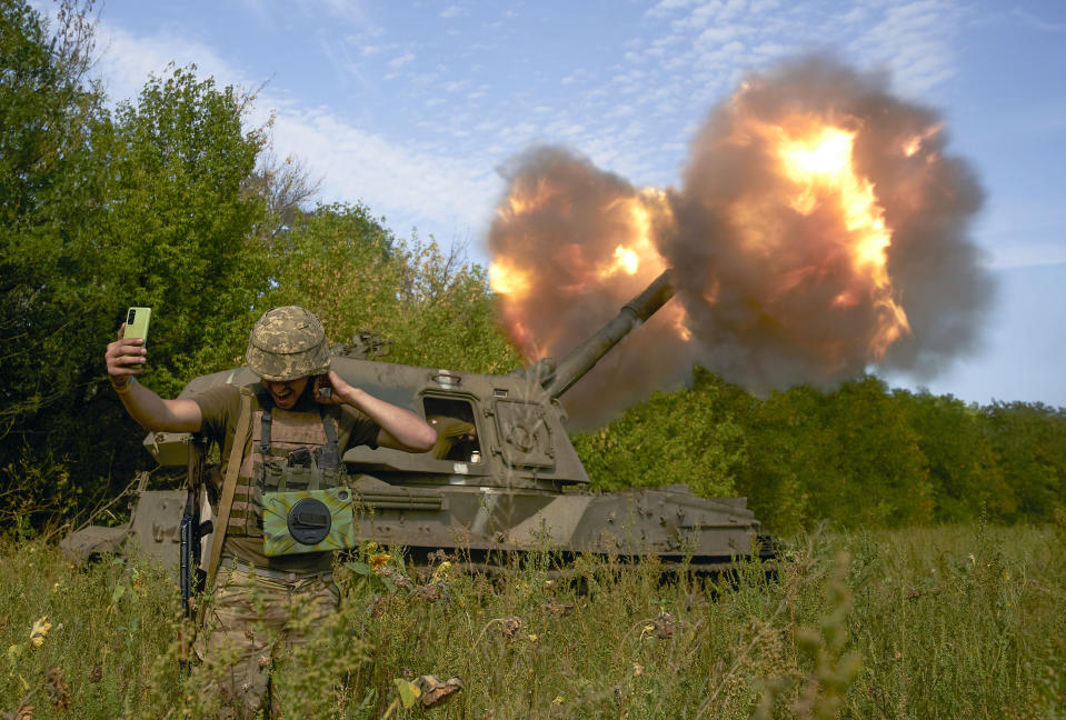 Un soldado ucraniano se toma una selfie mientras un sistema de artillería dispara un proyectil el sábado 3 de septiembre de 2022, en la línea del frente en la región de Donetsk, en el este de Ucrania. (AP Foto/Kostiantyn Liberov)