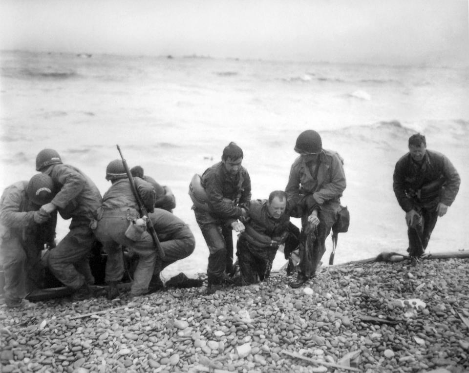 FILE - In this June 6, 1944, file photo, members of an American landing unit help their comrades ashore during the Normandy invasion. The men reached the zone code-named Utah Beach, near Sainte- Mere-Eglise, on a life raft after their landing craft was hit and sunk by German coastal defenses. (Louis Weintraub/Pool Photo via AP, File)