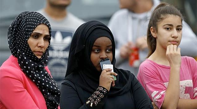 Residents gather outside a police barrier near the home where a woman was reportedly beheaded. Photo: AFP/Adrian Dennis