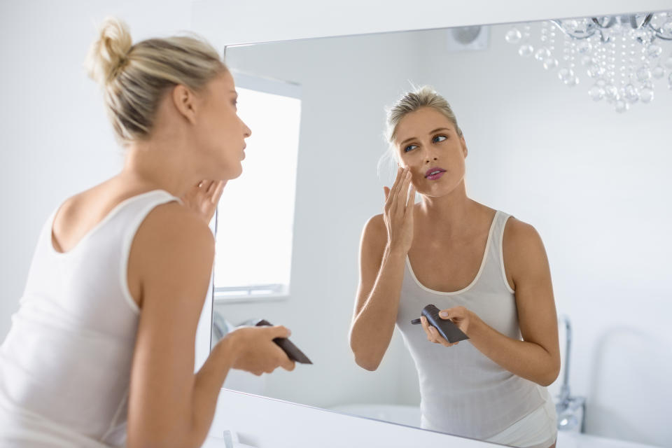 woman applying bronzing drops to face