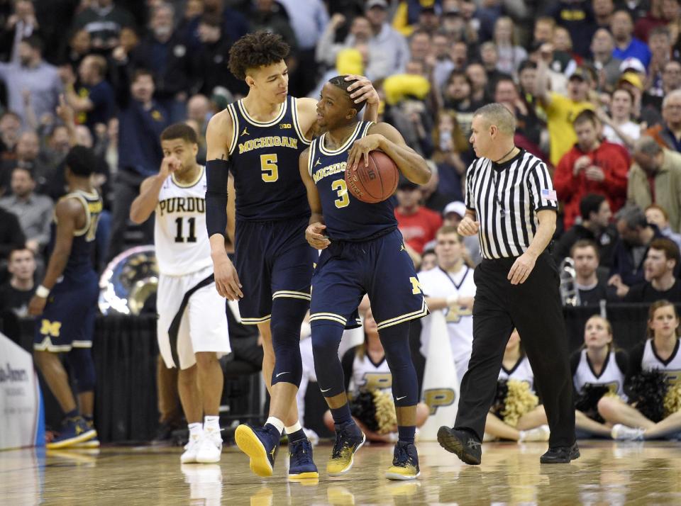 Michigan forward D.J. Wilson (5) and guard Xavier Simpson (3) react during the overtime of an NCAA college basketball game in the Big Ten tournament as Purdue guard P.J. Thompson (11) is seen at back, Friday, March 10, 2017, in Washington. Michigan won 74-70 in overtime. (AP Photo/Nick Wass)