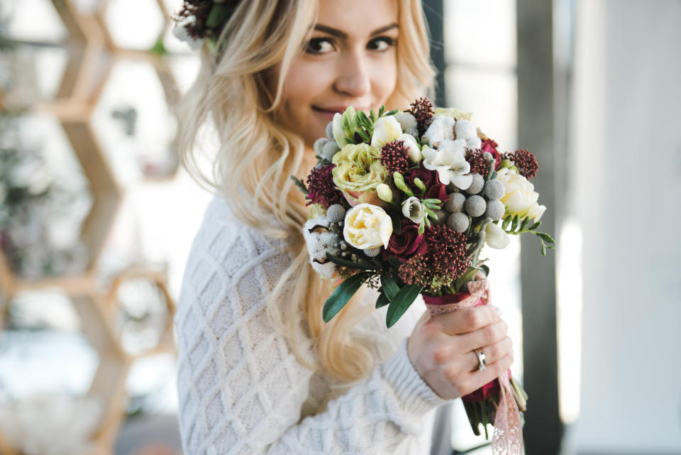 Portrait of Beautiful young bride in white wedding knitted dress with nice bouquet of flowers