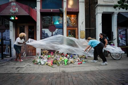 Mourners cover a memorial for those lost in Sunday morning's mass shooting in front of Ned Peppers Bar as a storm approaches in Dayton