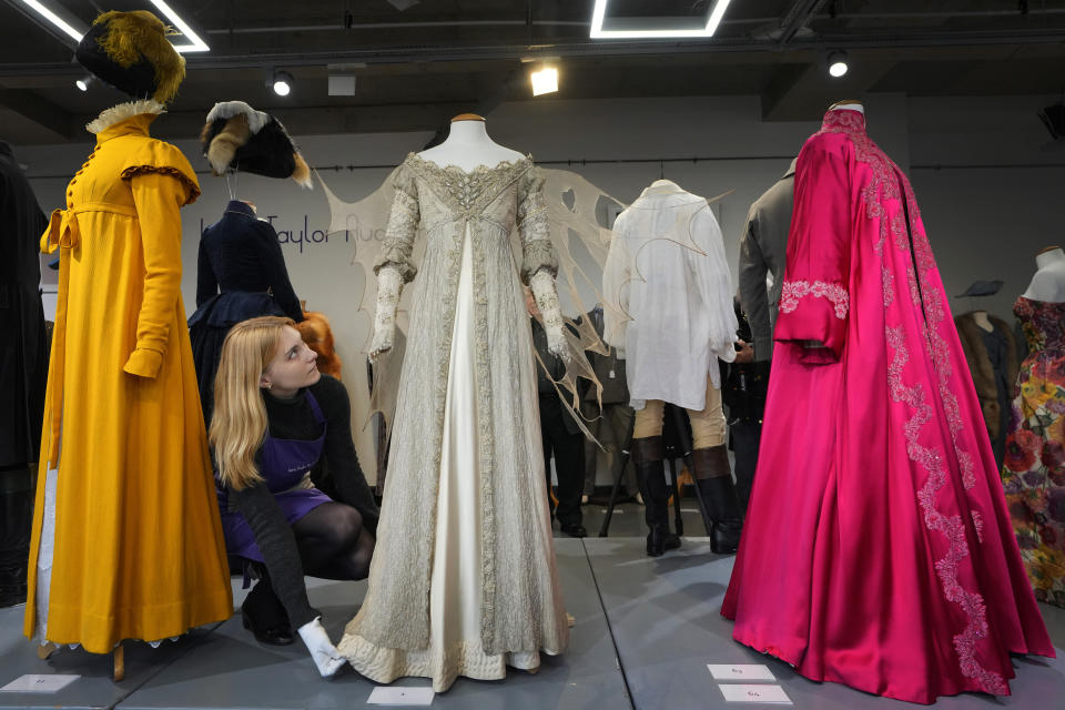 A costume handler arranges Drew Barrymore's costume as Danielle in the film Ever After A Cinderella Story, 1998, as it is displayed at Kerry Taylor Auctions in London, Tuesday, Feb. 27, 2024. The costume estimated at 1,000-1,500 UK Pounds (1,300-1,900 US Dollars) is one of 69 that will be for auction in the Lights Camera Auction event on March 5. The costumes have been donated by Cosprop in support of The Bright Foundation, an arts education charity, established and funded by John Bright, to provide life-enhancing, creative experiences for children and young people facing disadvantage. (AP Photo/Kirsty Wigglesworth)