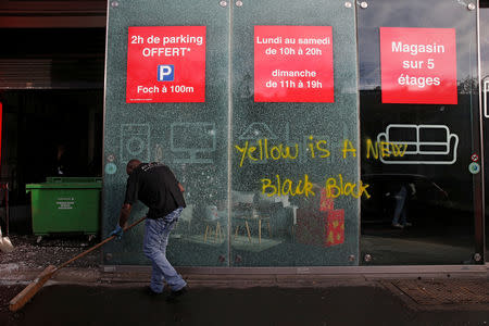 A man sweeps outside a vandalized store the morning after clashes with protesters wearing yellow vests, a symbol of a French drivers' protest against higher diesel fuel taxes, in Paris, France, December 2, 2018. REUTERS/Stephane Mahe