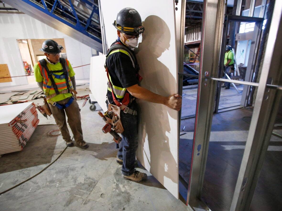 Construction workers install sheets of drywall at a building project in Calgary in a file photo from 2016.   (The Canadian Press - image credit)