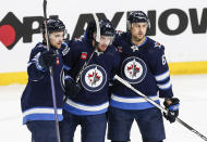 Winnipeg Jets' Neal Pionk (4), Nate Schmidt (88) and Nino Niederreiter (62) celebrate after Schmidt's goal against the Anaheim Ducks during second-period NHL hockey game action in Winnipeg, Manitoba, Friday, March 15, 2024. (John Woods/The Canadian Press via AP)