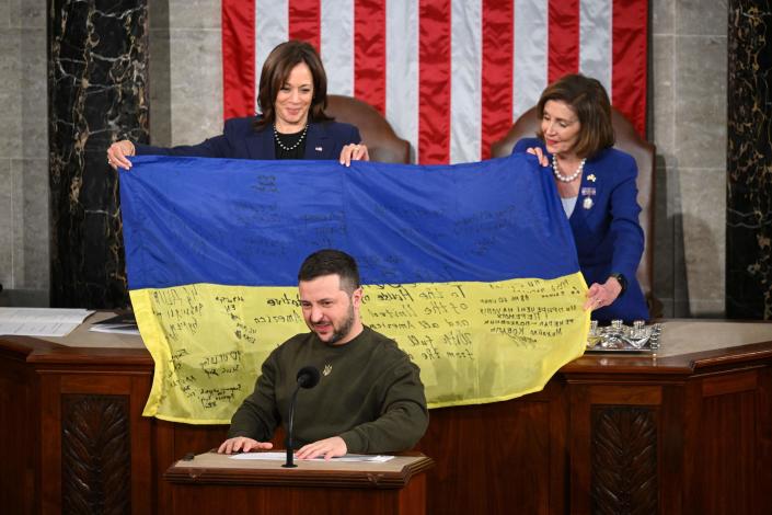 Ukraine's President Volodymyr Zelenskyy addresses Congress as Vice President Kamala Harris, left, and House Speaker Nancy Pelosi hold a flag signed by Ukrainian armed forces, at the U.S. Capitol, December 21, 2022.&nbsp; / Credit: MANDEL NGAN/AFP via Getty Images