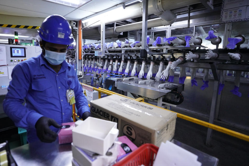 In this file picture taken Wednesday, Aug. 26, 2020, a worker packs disposable gloves at the Top Glove factory in Shah Alam on the outskirts of Kuala Lumpur, Malaysia. Malaysia's Top Glove Corp., the world's largest rubber glove maker, said Tuesday it expects a delay in deliveries after it was hit by a coronavirus outbreak that affected thousands of workers. (AP Photo/Vincent Thian)