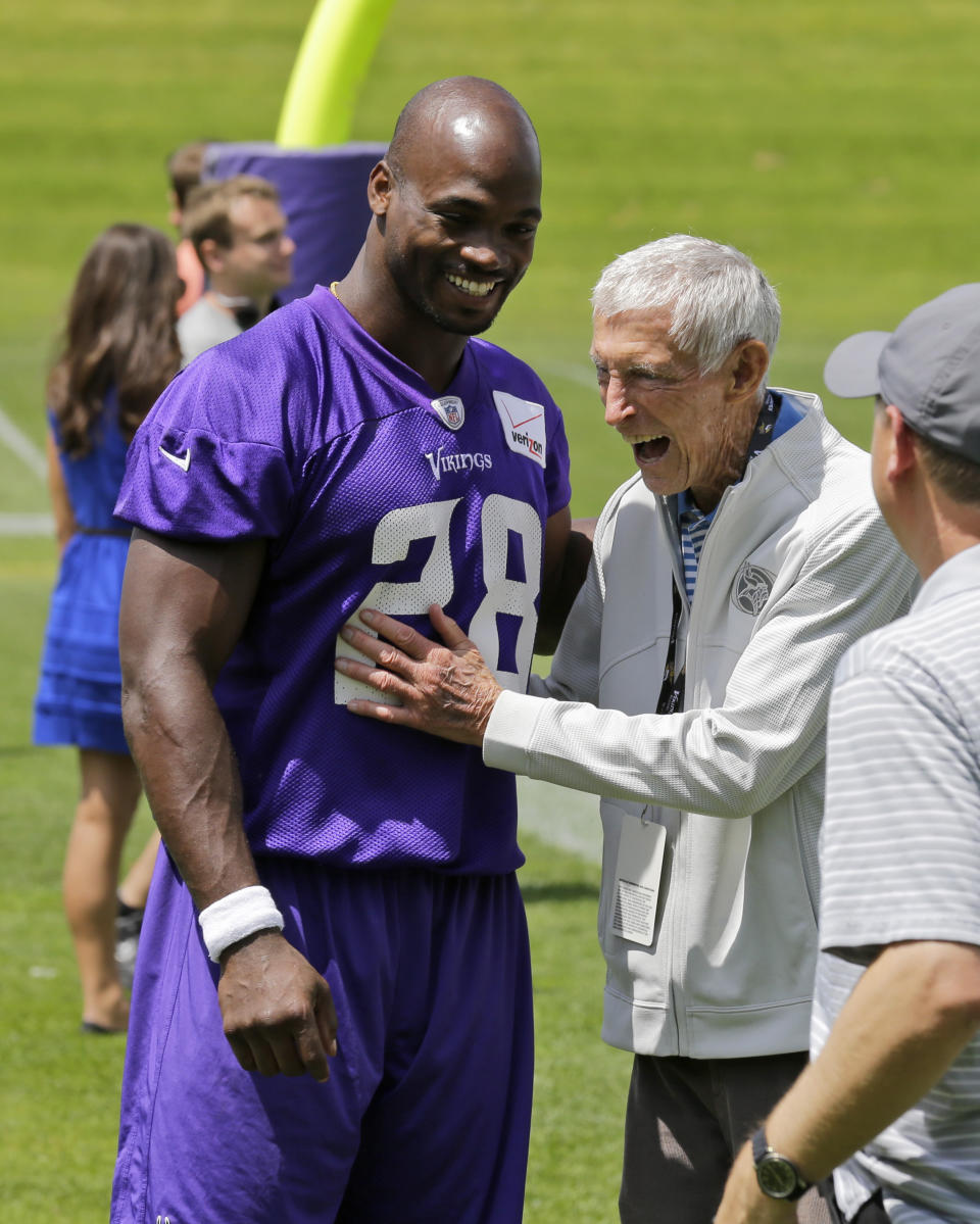 FILE - In this June 18, 2015, file photo, Minnesota Vikings running back Adrian Peterson, left, laughs with former Vikings coach Jerry Burns, right, during NFL football minicamp in Eden Prairie, Minn. Burns, the colorful character who took over as the Vikings' head coach in a time of turmoil and led the team to three playoff berths, has died. He was 94. The team announced Burns’ death. Vikings spokesman Bob Hagan said Burns’ son-in-law informed him of Burns’ death Wednesday morning, May 12, 2021. (AP Photo/Ann Heisenfelt, File)