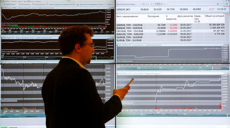 A man uses his mobile phone next to an information screen at the Moscow Exchange in Moscow, Russia, May 26, 2017. REUTERS/Segrei Karpukhin