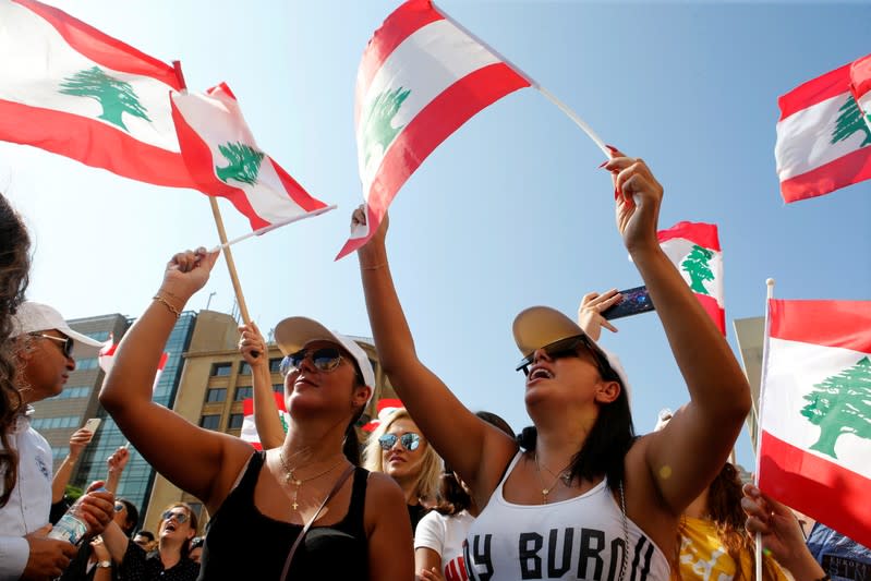 Demonstrators carry national flags during an anti-government protest in Beirut