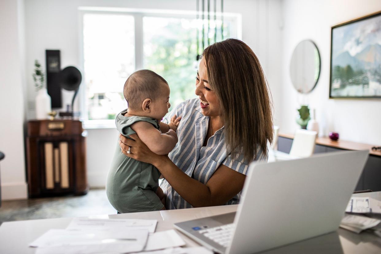 Mother working from home while holding baby