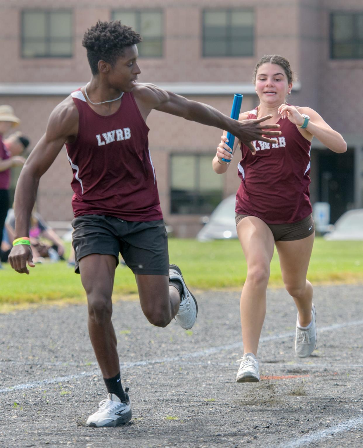 LWRB senior Lauren Crumrine, right, hands the baton off to teammate and junior Brendin Melton in the co-ed 4x100-meter relay during the first annual Cinder Classic track and field meet Saturday, May 4, 2024 in Roanoke.