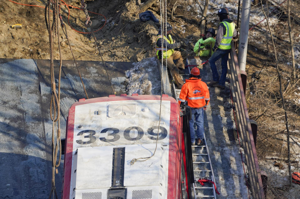 Workers use ladders placed along the sides of the bus that was on a bridge when it collapsed Friday as they work to remove it during the recovery process on Monday Jan. 31, 2022 in Pittsburgh's East End. (AP Photo/Gene J. Puskar)