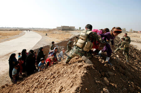 Kurdish Peshmerga fighters help Iraqi women and children climb over a berm as they were escaping the Islamic State controlled village of Abu Jarboa at the frontline, Iraq October 31, 2016. REUTERS/Azad Lashkari