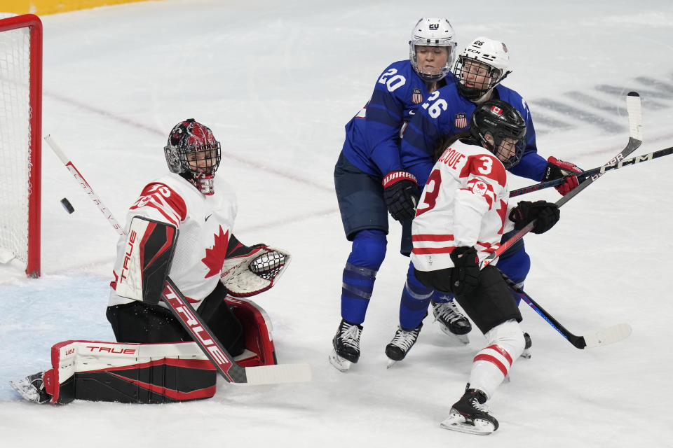 Canada goalkeeper Ann-Renee Desbiens (35) deflects a shot as Jocelyne Larocque (3) defends against United States' Hannah Brandt (20) and Kendall Coyne Schofield (26) during a preliminary round women's hockey game at the 2022 Winter Olympics, Tuesday, Feb. 8, 2022, in Beijing. (AP Photo/Petr David Josek)